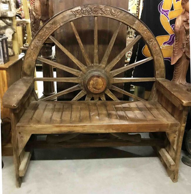 Grand banc en bois avec une roue de chariot ancien