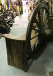 Grand banc en bois avec une roue de chariot ancien