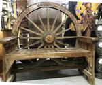 Grand banc en bois avec une roue de chariot ancien